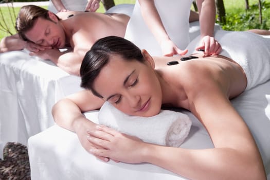 Couple receiving hot stone therapy from massage therapists