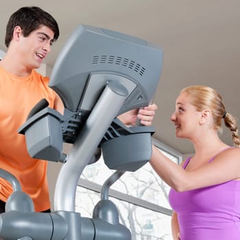 Woman talking to a man working out on a stepping machine in a gym