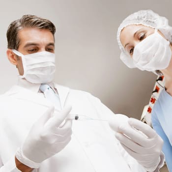 Lab technician injecting into an egg with her colleague standing beside him