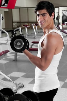 Portrait of a man exercising with dumbbell in a gym