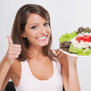 Woman making a thumbs up sign with a plate of salad