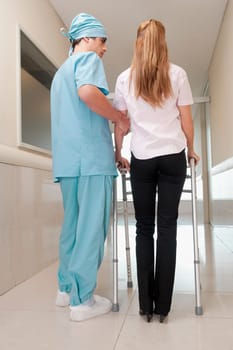 Doctor assisting a patient to walk in a hospital corridor