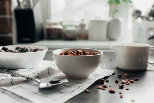 Frozen blackberries, granola, cream, towel on table. Blurred background. High quality photo