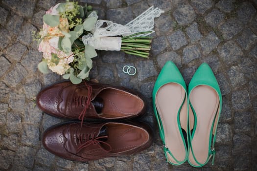 Wedding bouquet, shoes, rings on the stone tile. Blurred background. High quality photo