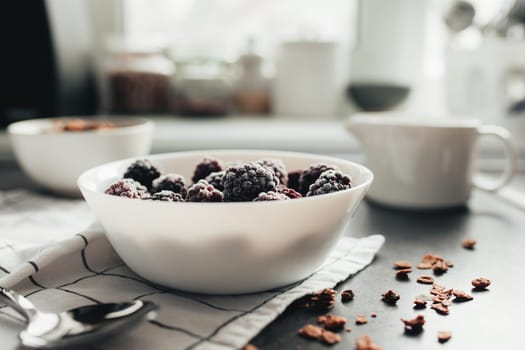 Frozen blackberries, granola, cream, towel on table. Blurred background. High quality photo