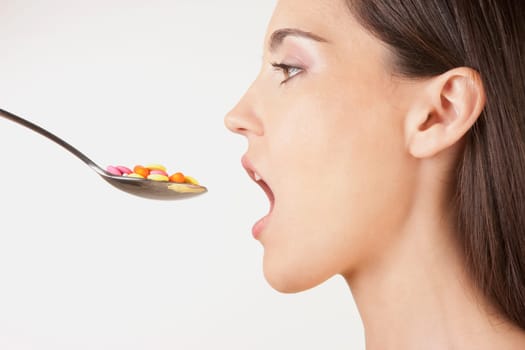 Close_up of a woman taking a spoonful of pills