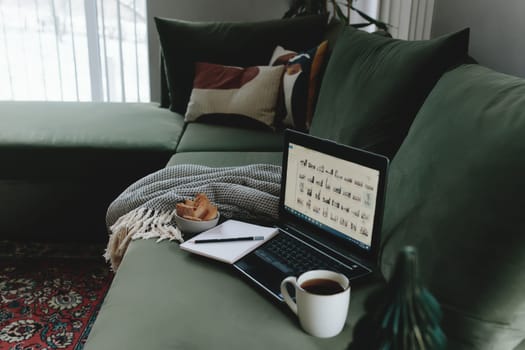 Laptop on the green sofa. Work from home. Loft or modern interior. High quality photo