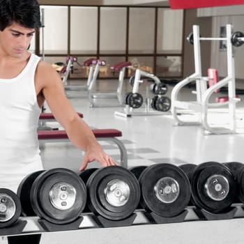 Man choosing dumbbells in a gym