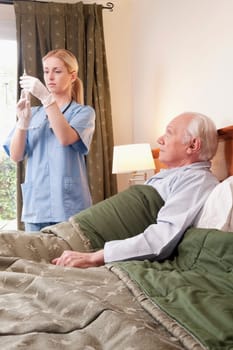 Female nurse holding a syringe and standing near a patient