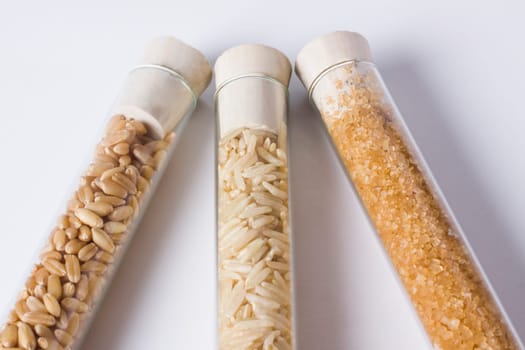 Close_up of brown rice and sugar with wheat in test tubes