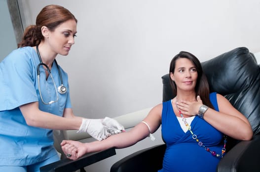 Female doctor taking blood sample of a pregnant woman