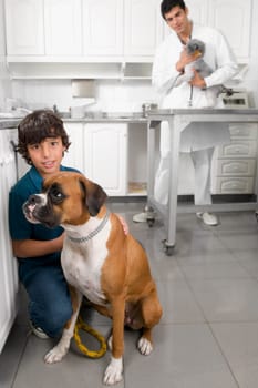 Boy stroking a dog with a vet in the background