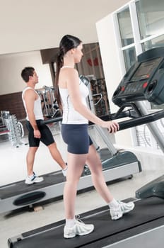 Woman and a man walking on treadmills