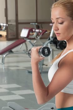Close_up of a woman exercising with dumbbell at gym
