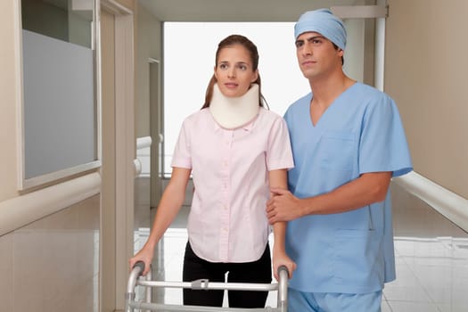 Doctor assisting a patient to walk in a hospital corridor