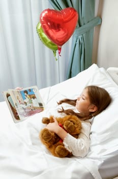 Girl reading a comic book on a hospital bed