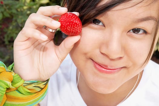 Woman holding a strawberry and smirking