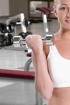 Close_up of a woman exercising with dumbbells at gym
