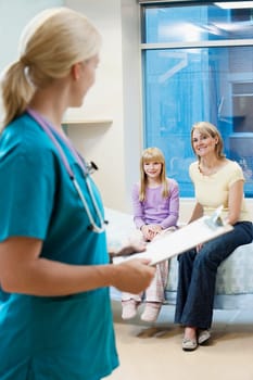 Female doctor holding a clipboard with patients in the background