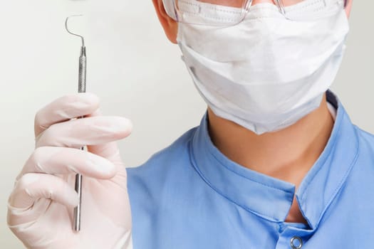 Close_up of a female dentist holding a dental scaler