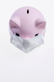 Close_up of a piggy bank wearing flu mask