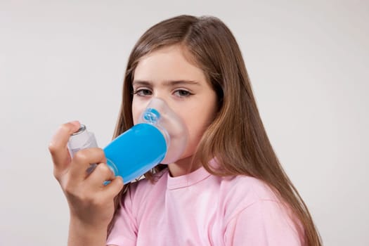 Girl using an asthma inhaler attached with a spacer