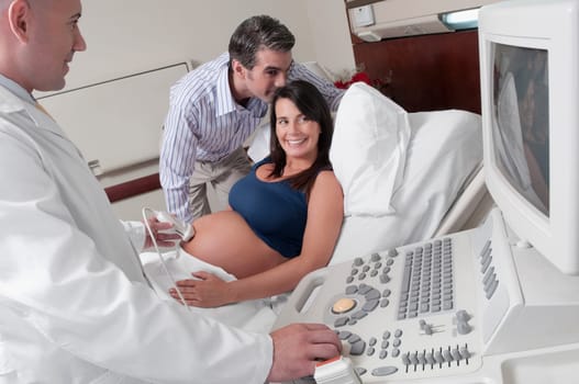 Pregnant woman going through an ultrasound scan with her husband beside her