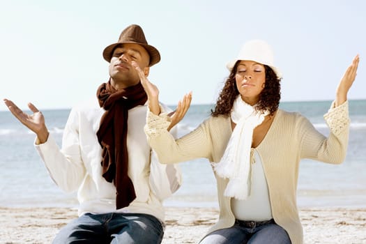 Couple meditating on the beach