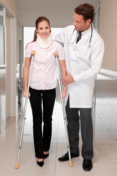 Doctor assisting a patient to walk in a hospital corridor
