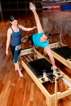Female instructor assisting a man in a gym
