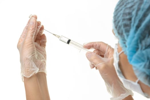A medical professional draws a medicine from an ampoule with a syringe