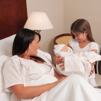 Woman with her newborn baby and daughter in a hospital