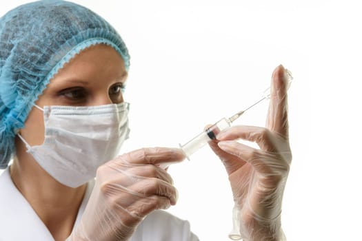 A nurse wearing a mask and gloves draws medicine with a syringe from an ampoule, isolated on a white background