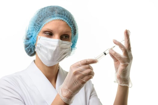 Nurse in mask and gloves draws medicine with a syringe from an ampoule