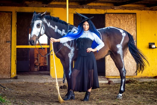 A girl dressed as a witch stands with a broom near a horse on which a skeleton is drawn