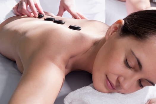 Woman receiving hot stone therapy from a massage therapist