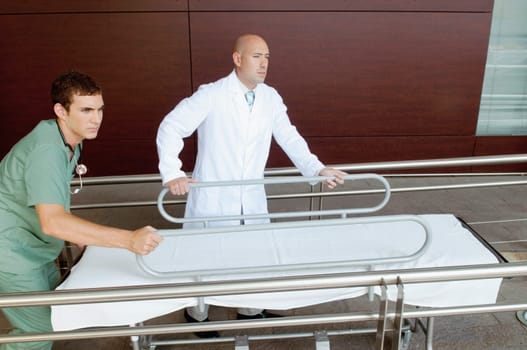 Doctor and a male nurse pushing a hospital gurney