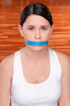Woman covering her mouth with a tape measure