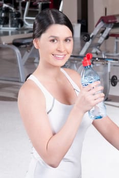 Portrait of a woman holding a water bottle in a gym