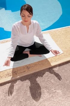 Woman practicing yoga at the poolside