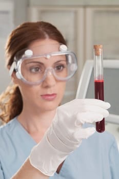 Female lab technician analyzing a blood sample in a test tube
