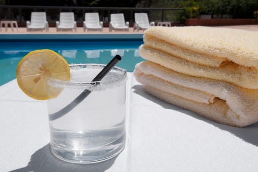 Glass of lemonade with towels at the poolside