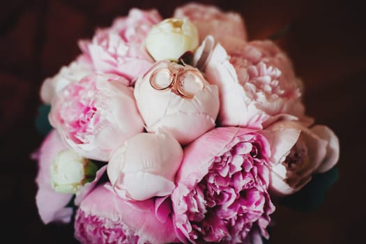 Pink rose bouquet with wedding rings on it. High quality photo