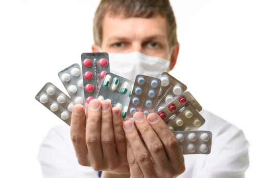 A man in a medical mask sips a fan of medicines into the frame, focusing on medicines