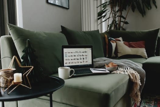 Laptop on the green sofa. Work from home. Loft or modern interior. High quality photo