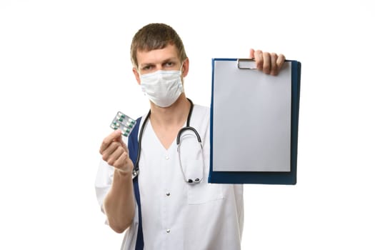 The doctor shows a tablet with a white sheet of paper in the frame, holds medicines in the other hand, focusing on the tablet