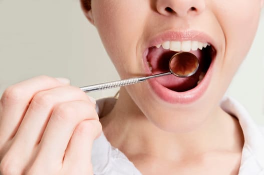 Woman examining her teeth with angled mirror