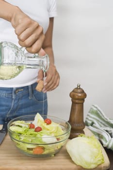Mid section view of a woman pouring oil in to a bowl