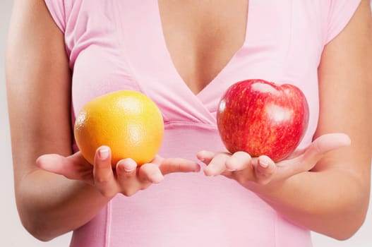 Woman holding an apple and an orange