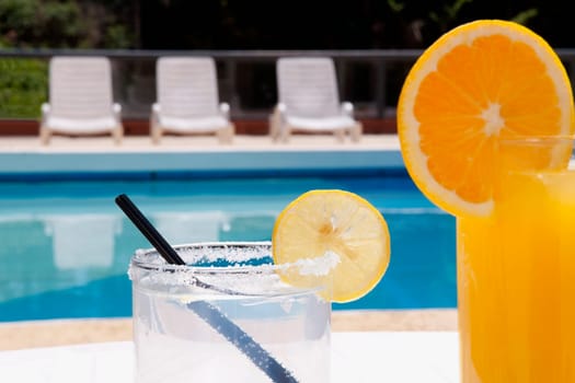 Lounge chairs with juices on table at the poolside